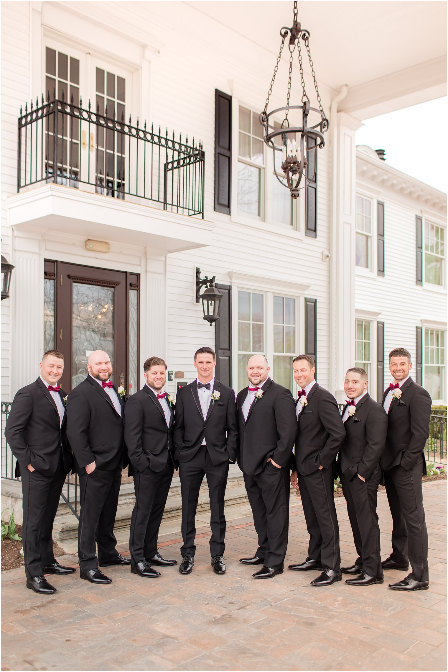 groom stands with groomsmen in black suits outside Park Savoy Estate