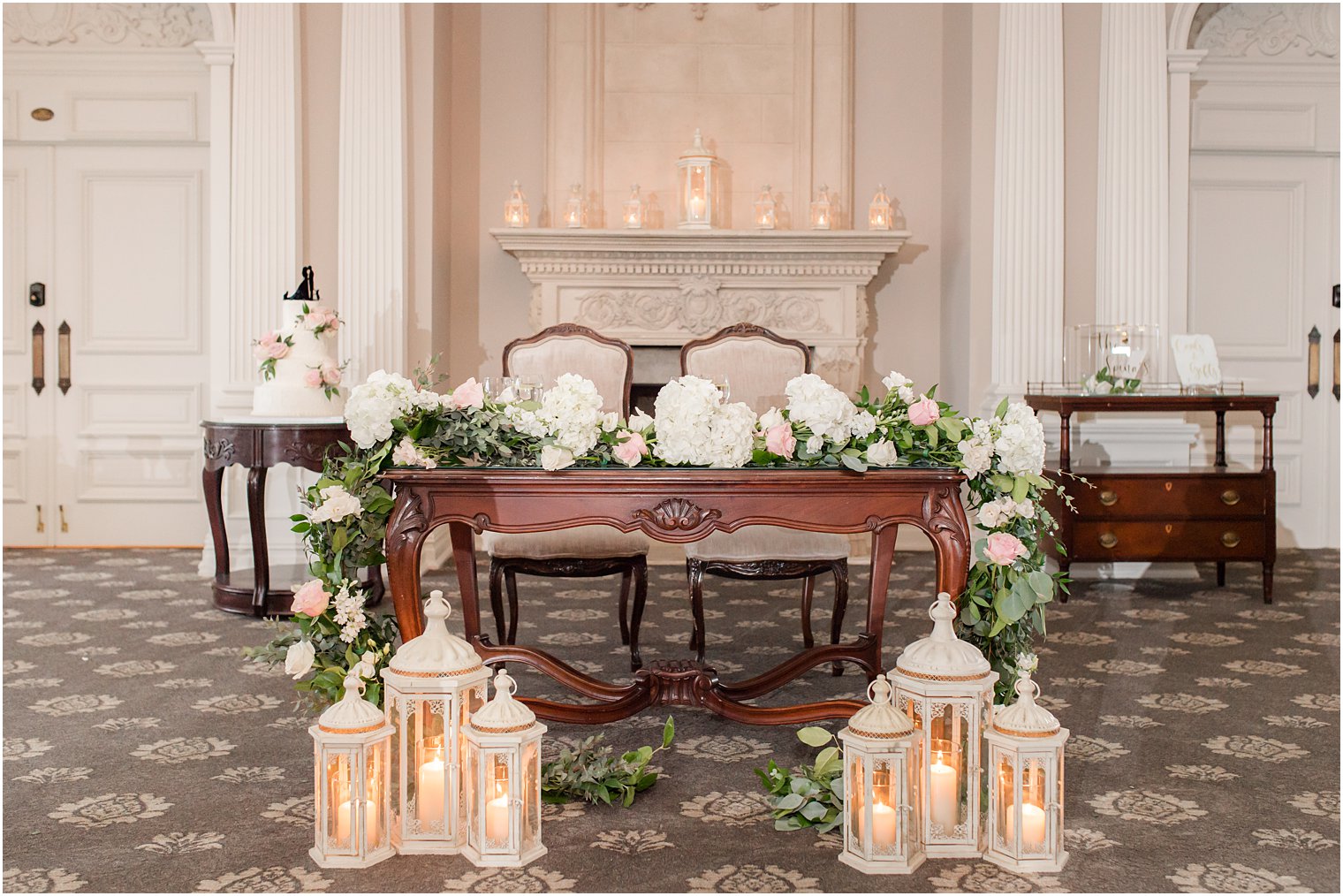 sweetheart table with ivory flowers and lanterns 