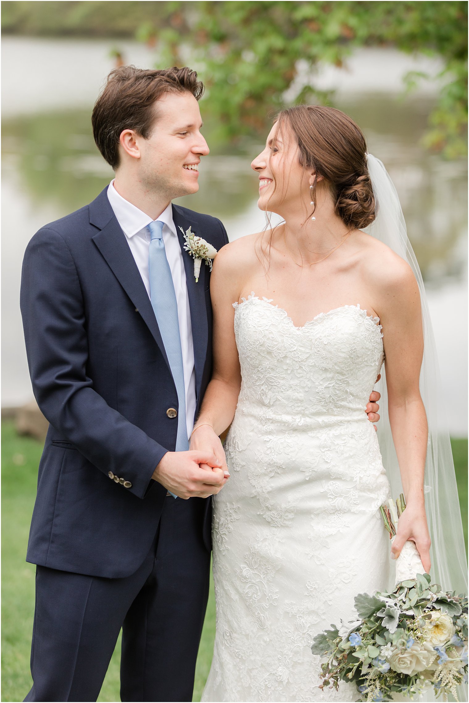 bride and groom hold hands smiling together by lake at Indian Trail Club