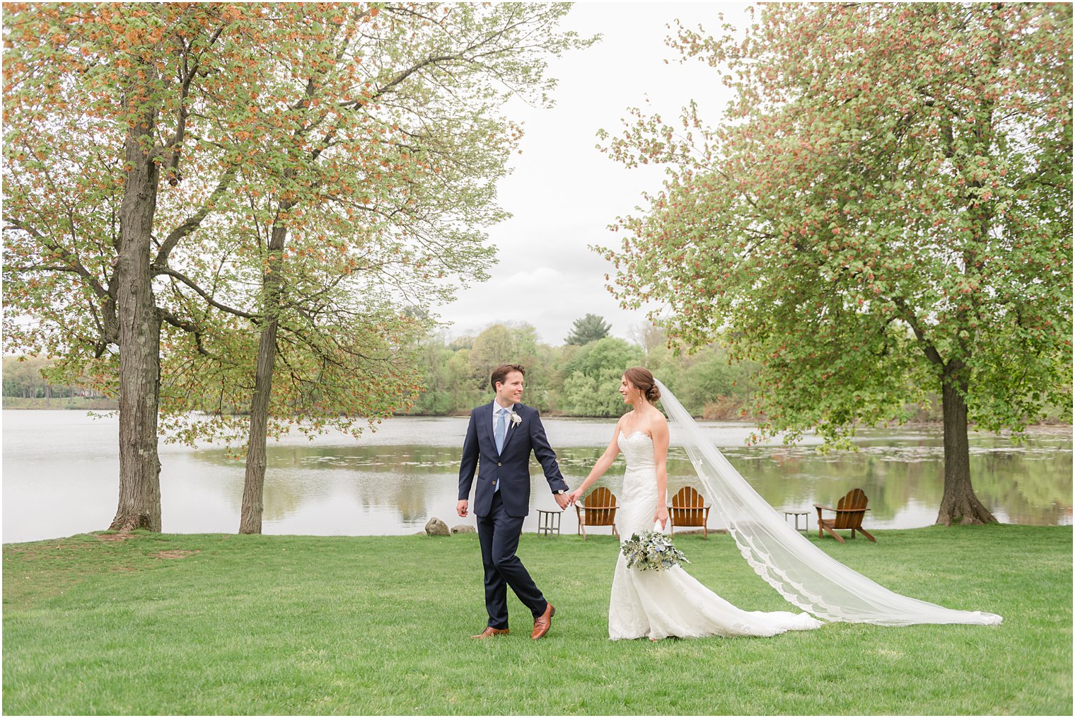 groom walks with bride leading her by lakefront at Indian Trail Club
