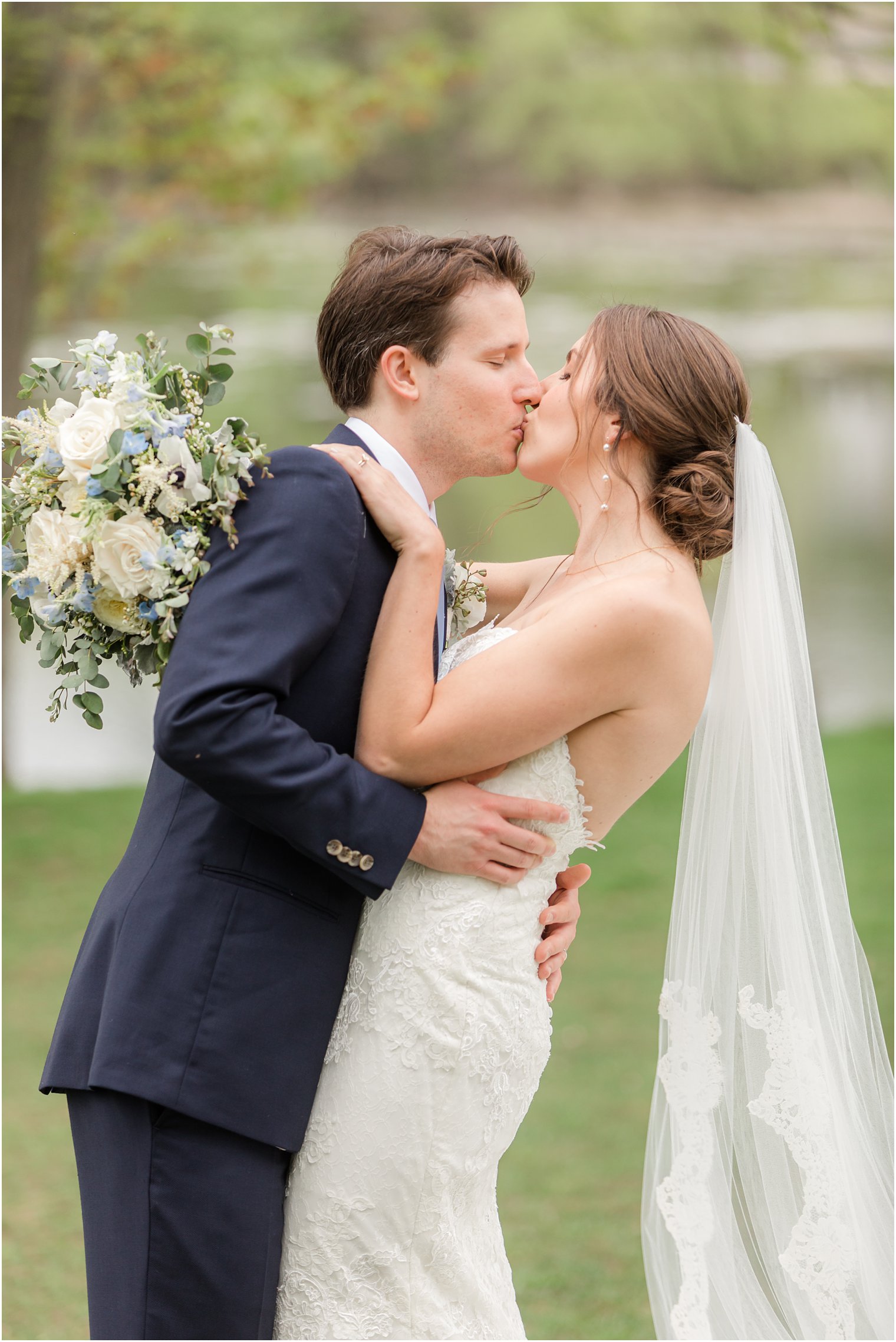 bride and groom kiss with veil draped behind them 