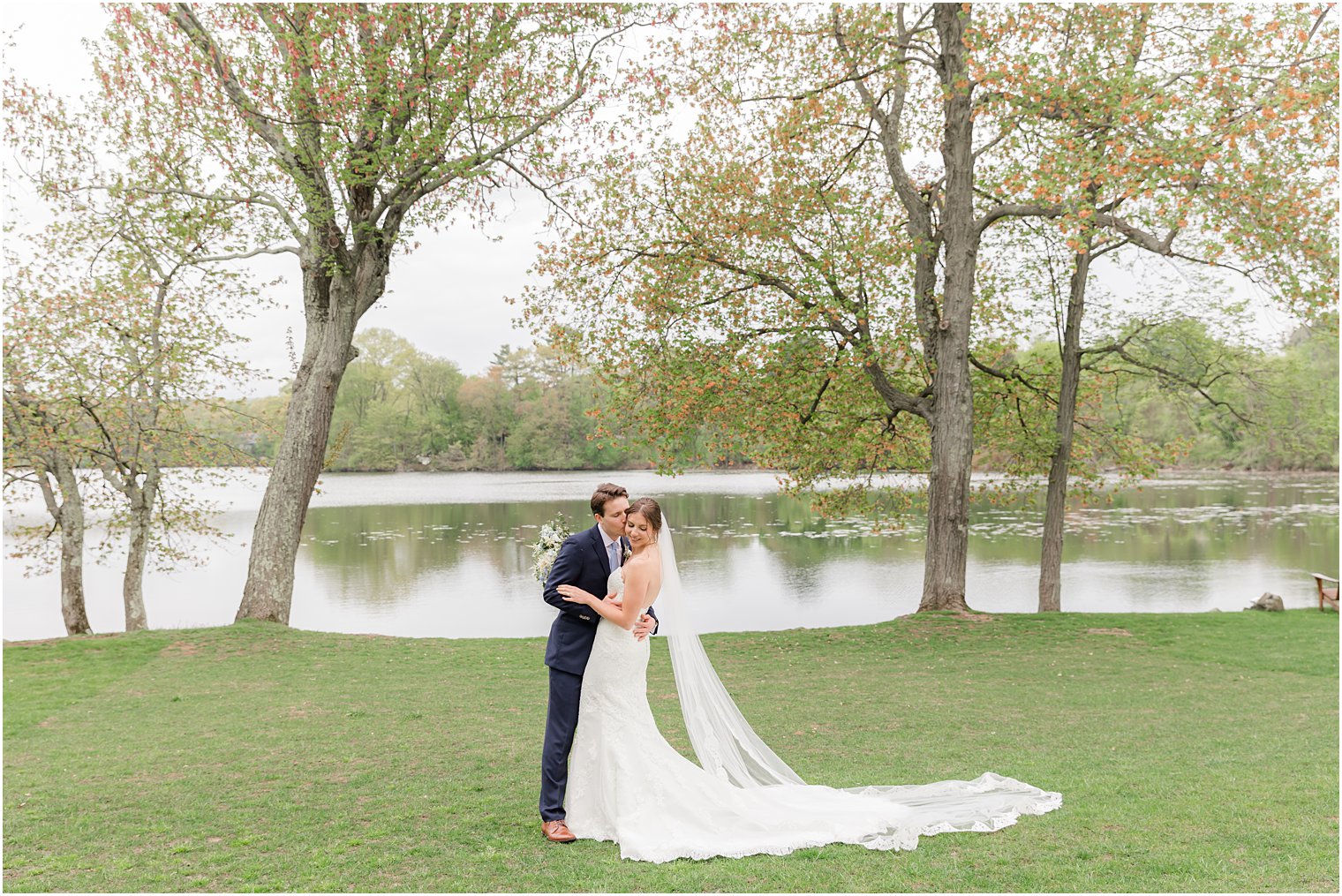 newlyweds kiss by lake on spring wedding day at Indian Trail Club