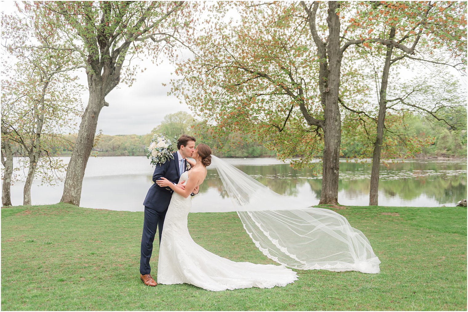 groom kisses bride dipping her by lake at Indian Trail Club