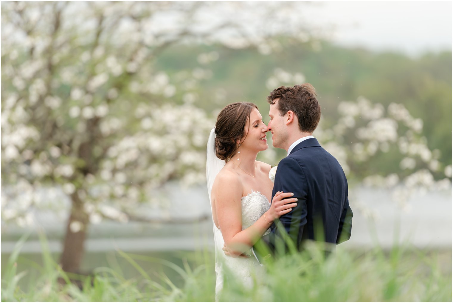 bride and groom lean to kiss by white tree at Indian Trail Club