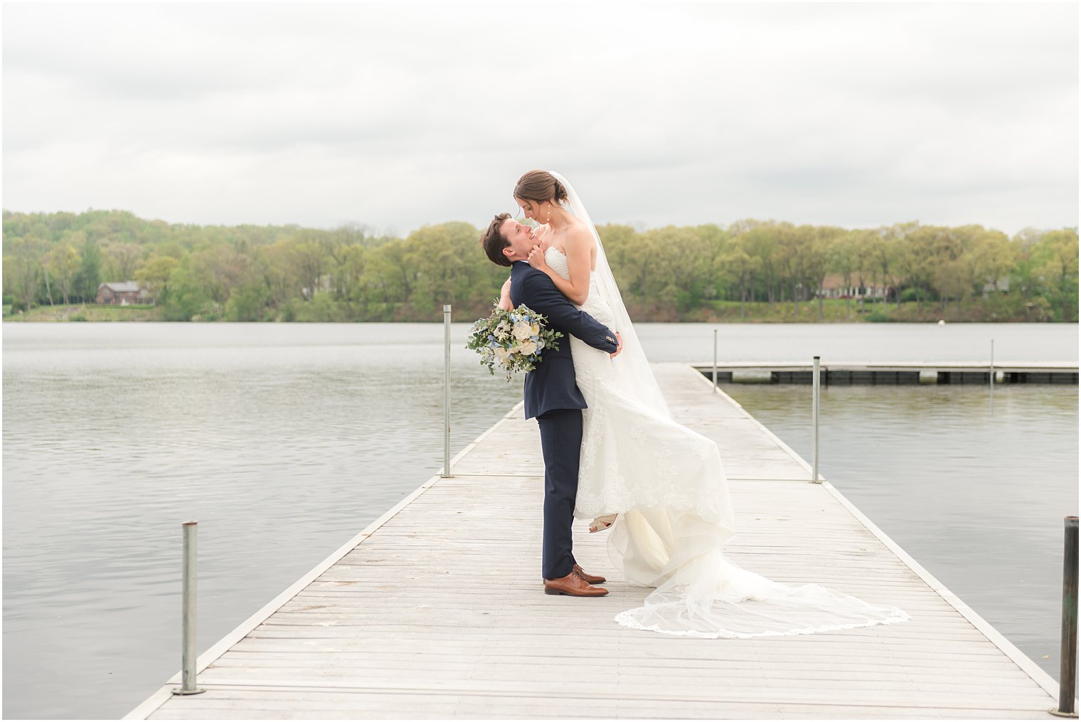 groom lifts bride up on dock during Indian Trail Club wedding portraits 