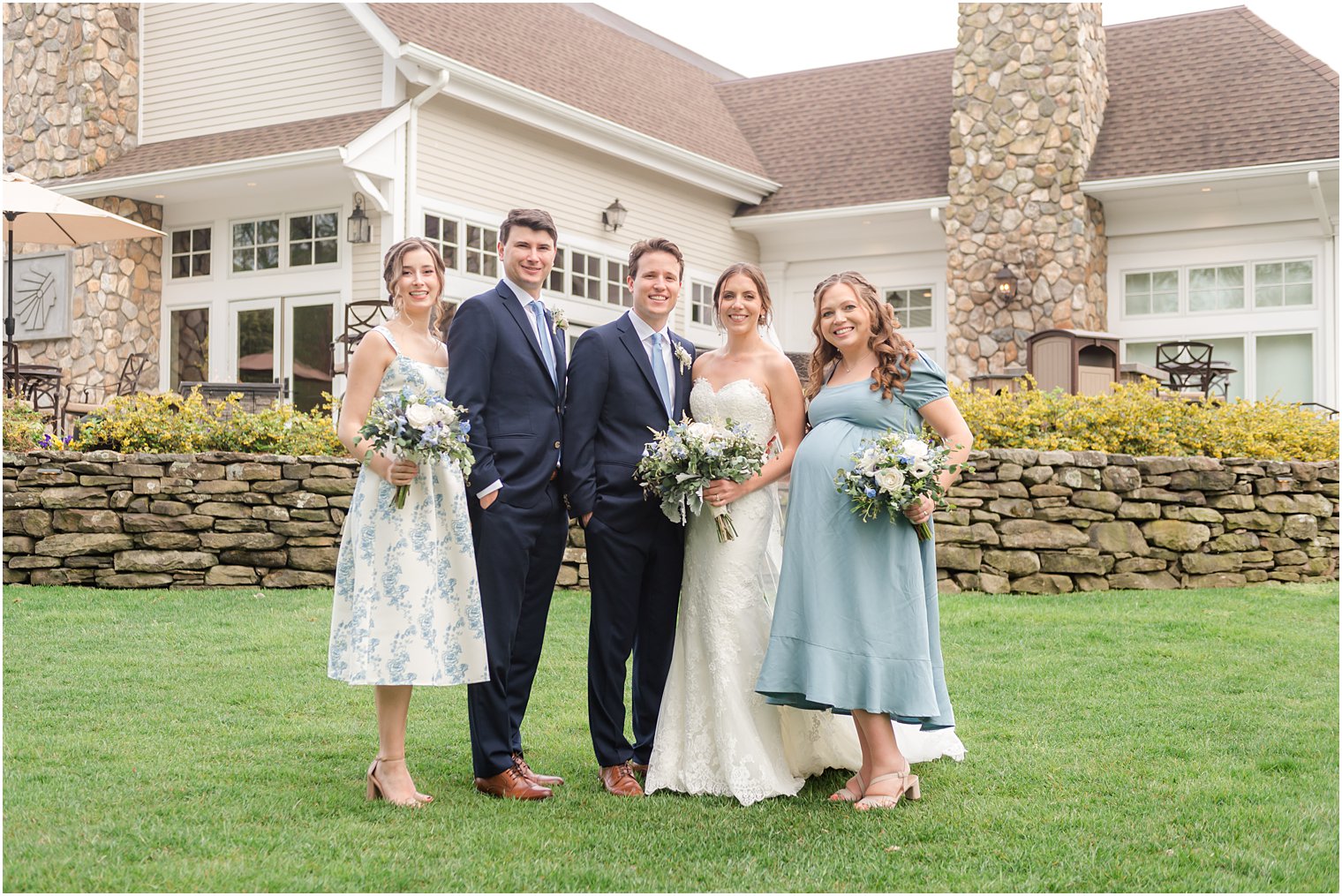 bride and groom stand with wedding party in blue by Indian Trail Club