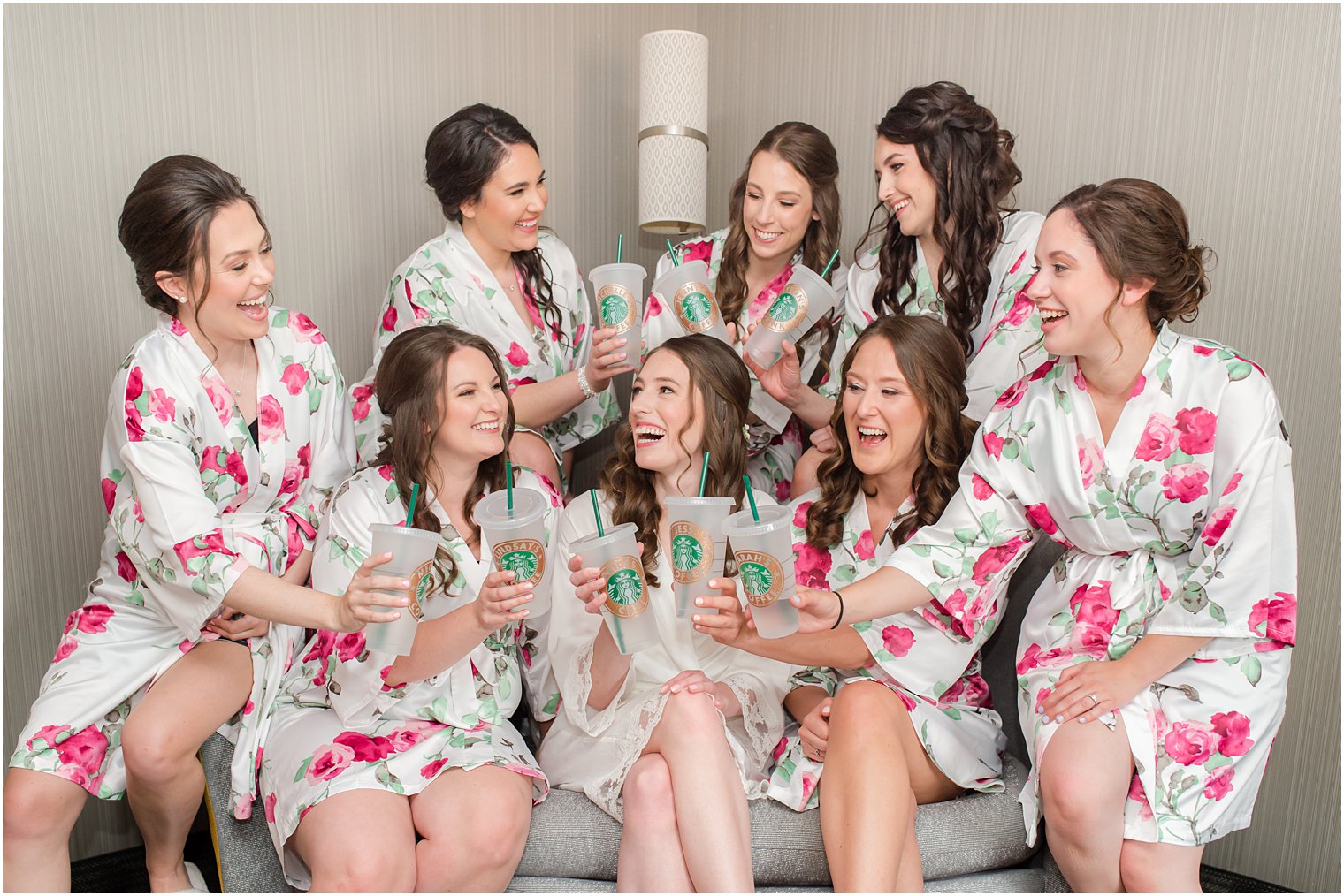 bride sits with bridesmaids laughing with Starbucks cups 
