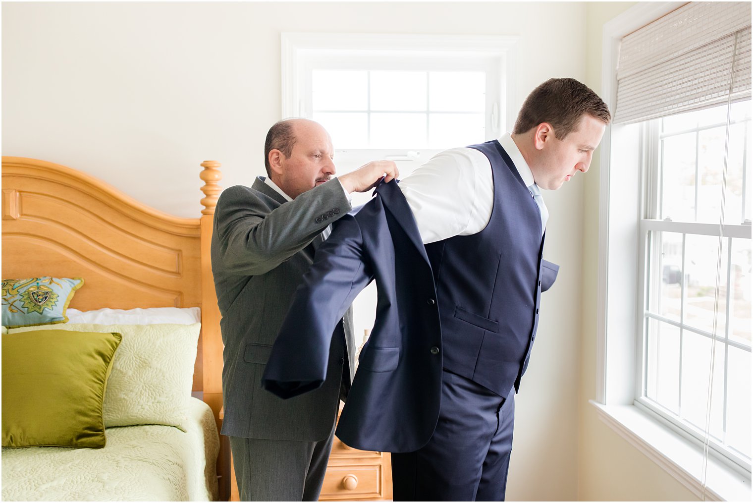 father helps groom into suite jacket at English Manor