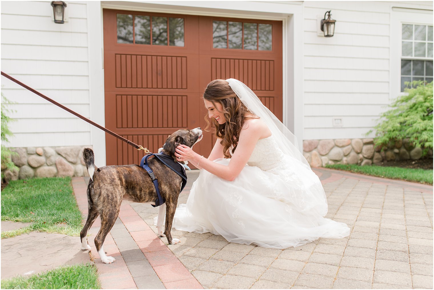 bride kneels down to pet dog on wedding day at The English Manor
