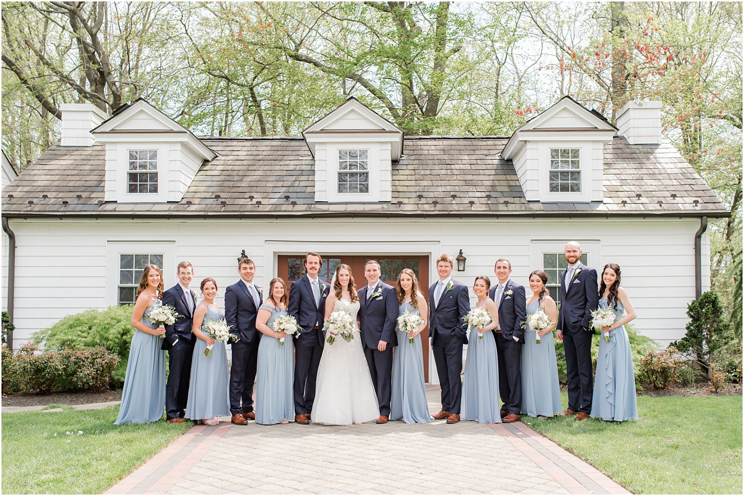 bride and groom stand with wedding party in blue and navy attire at The English Manor