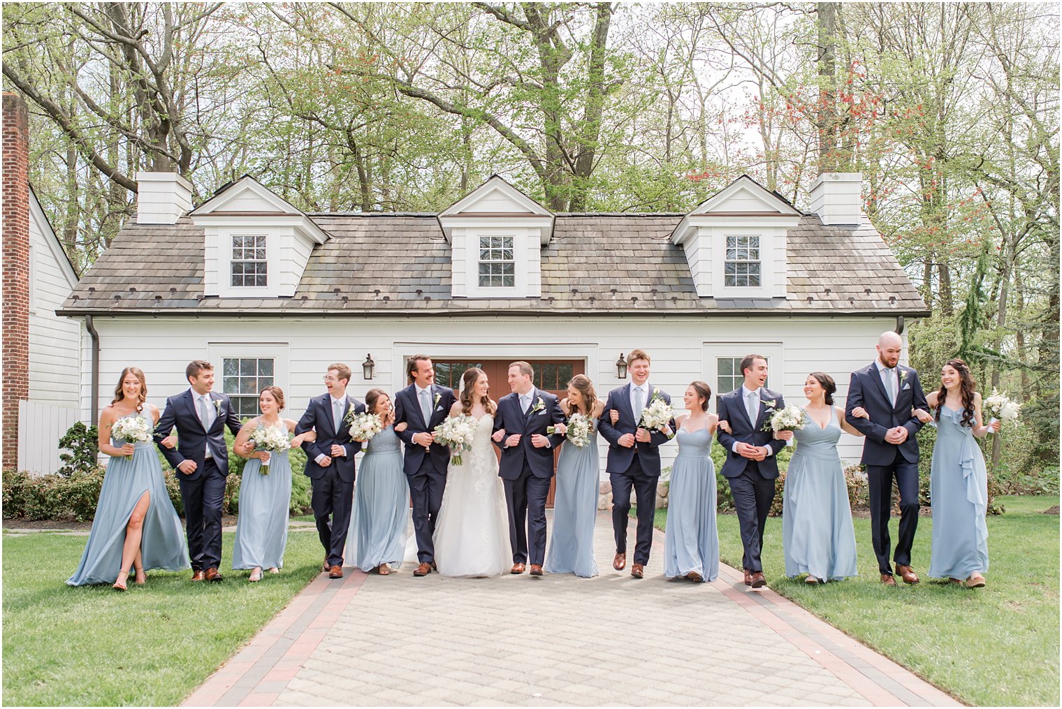 newlyweds stand with wedding party outside house at The English Manor
