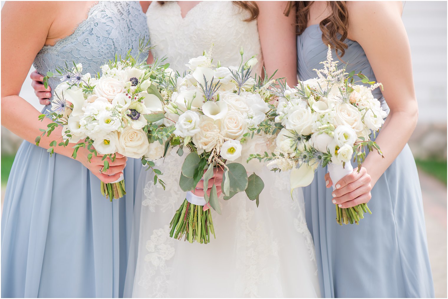 bride and bridesmaids hold bouquets of white flowers 