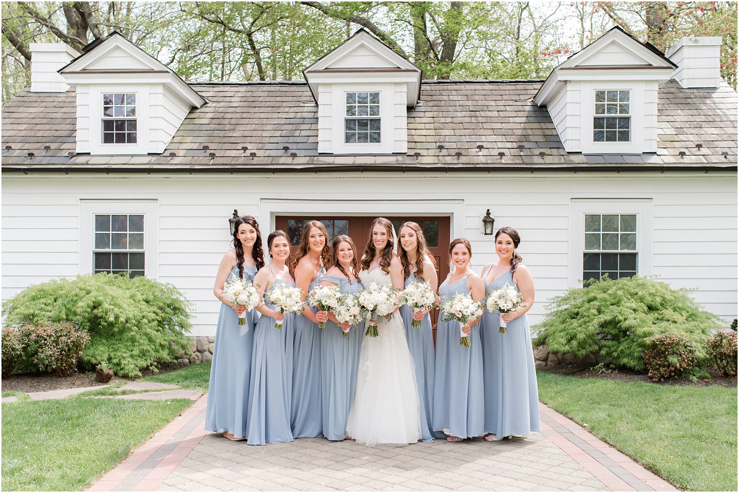 bride poses with bridesmaids in light blue gowns 