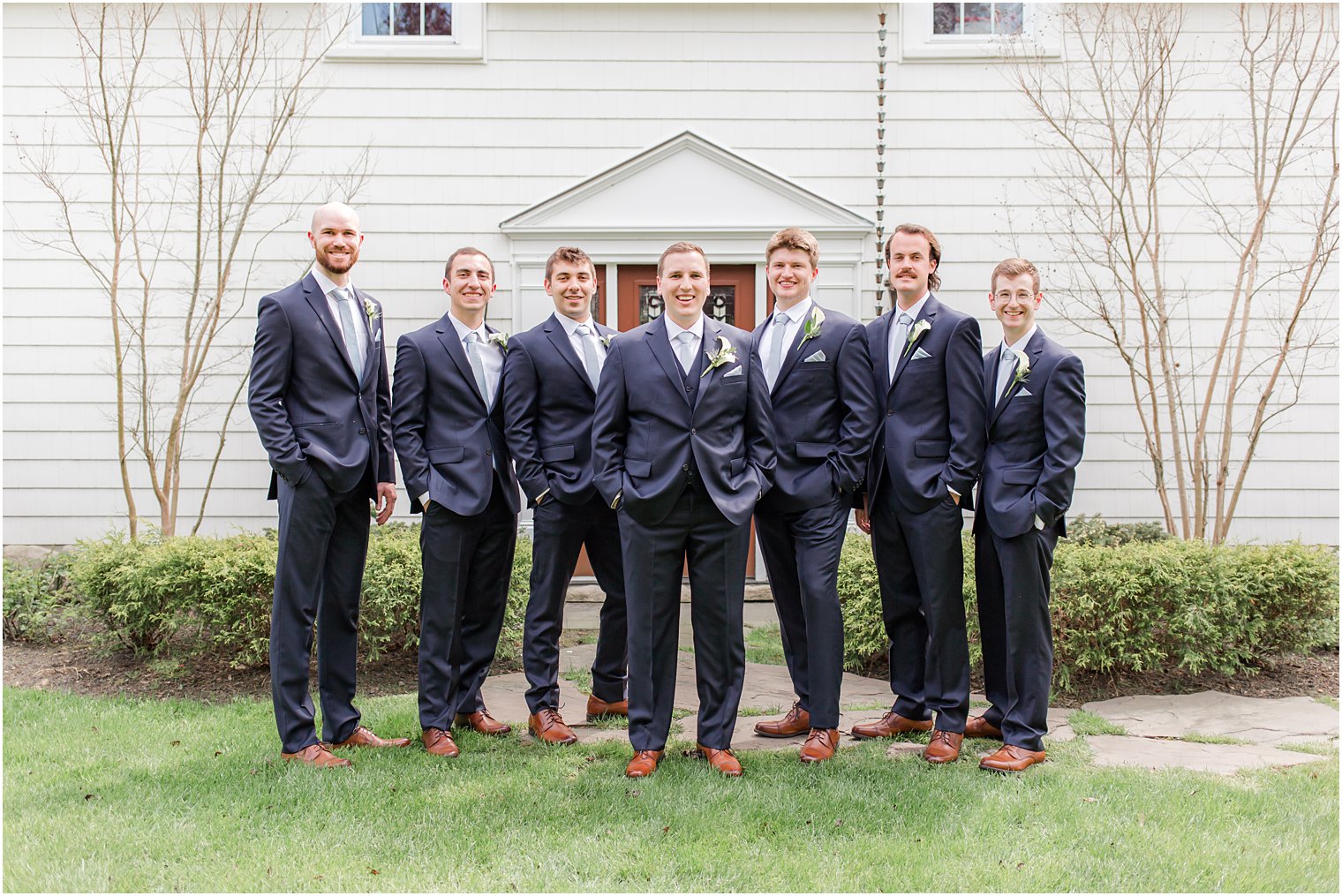 groom stands with groomsmen in navy suits at The English Manor