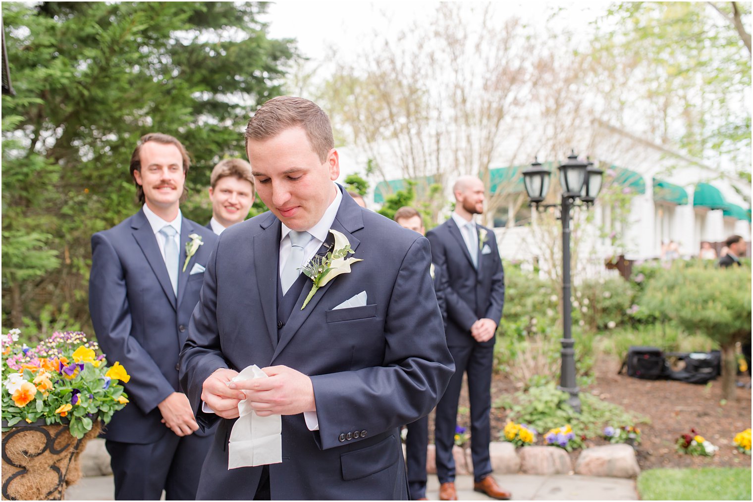 groom holds handkerchief in garden 