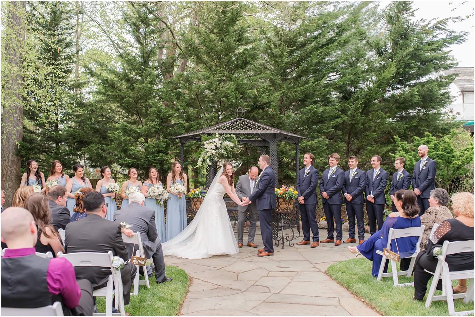 bride and groom hold hands during ceremony in gardens 