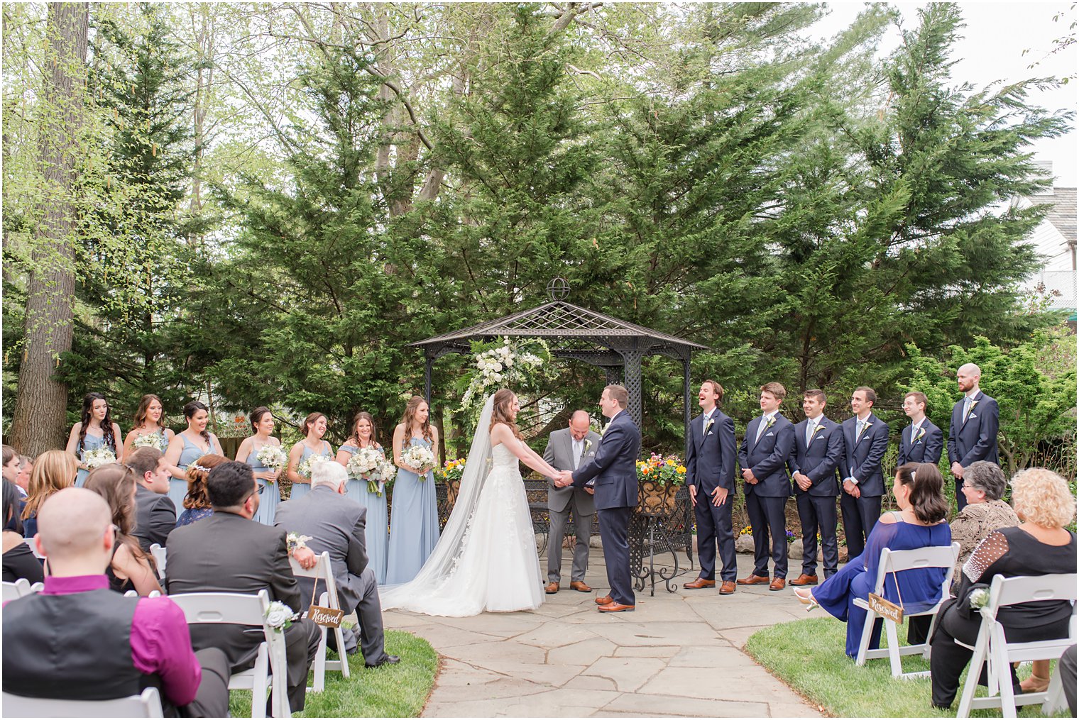 newlyweds hold hands during wedding ceremony in gardens 