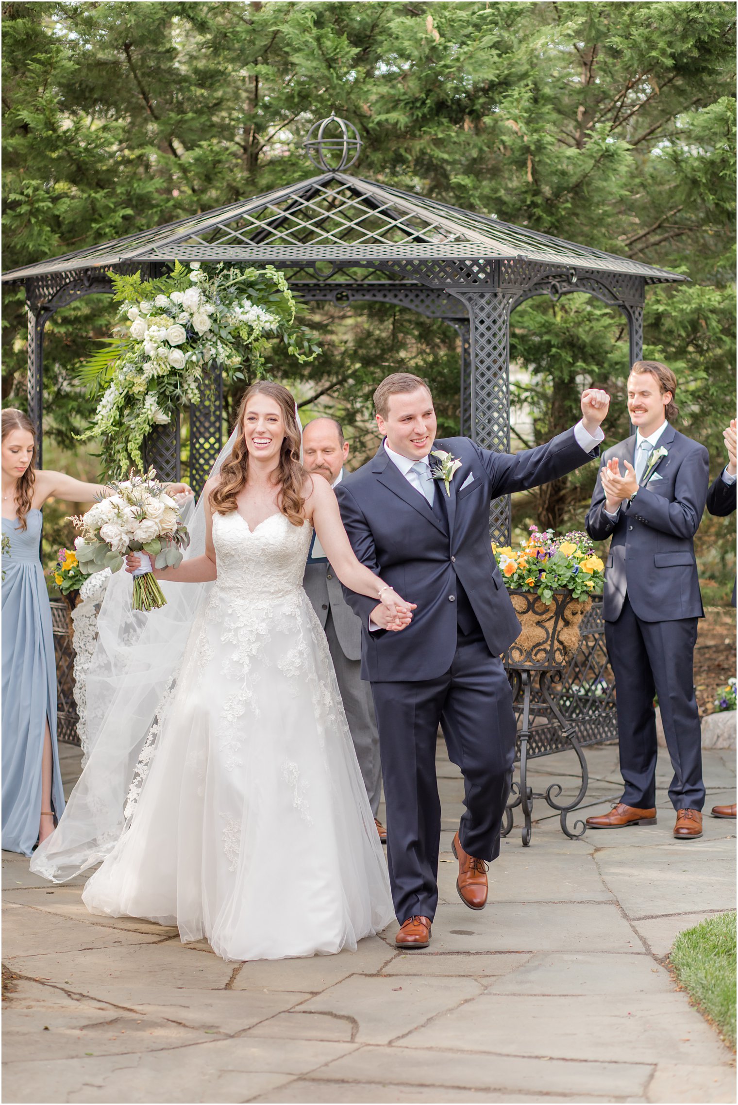 newlyweds cheer and wave to guests at garden wedding ceremony 