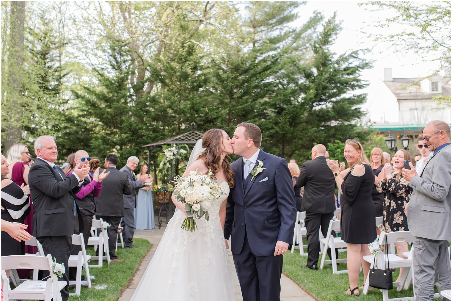 bride and groom kiss during garden wedding ceremony
