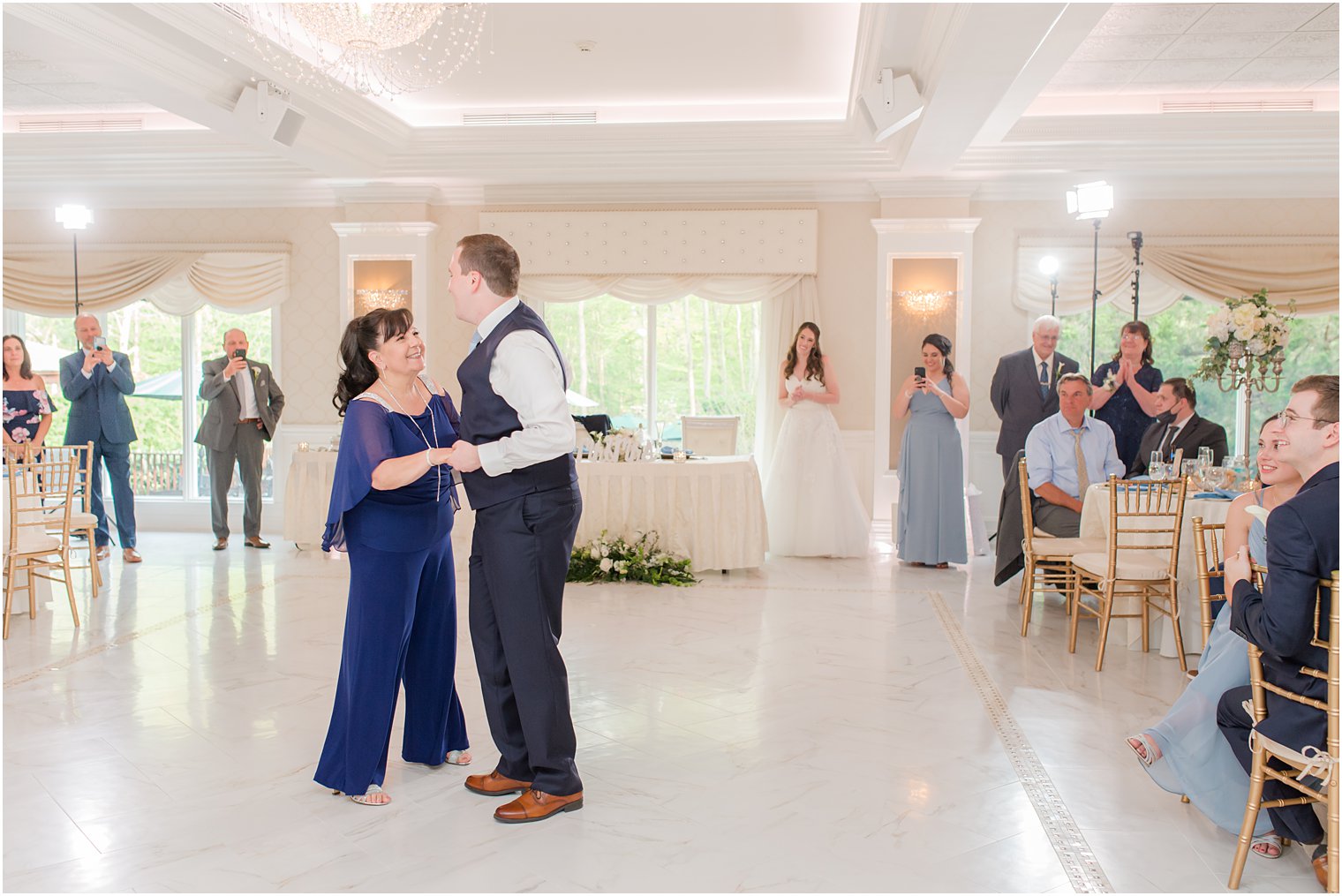 groom dances with mother in blue pantsuit at wedding reception 