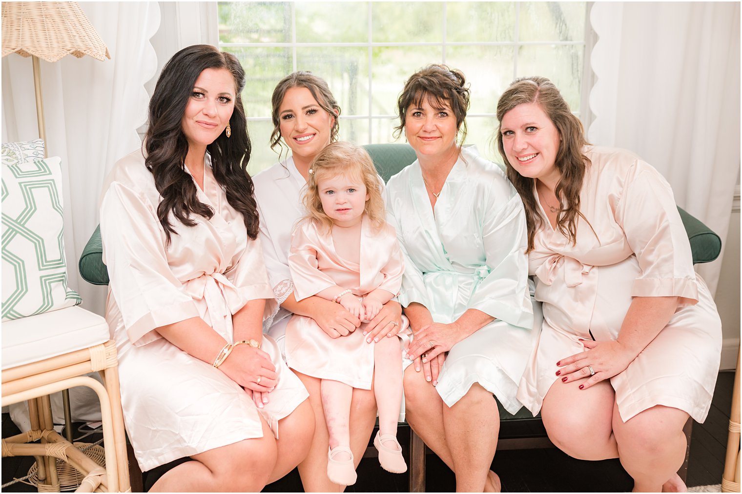 bride sits on couch with mother, bridesmaids, and flower girl