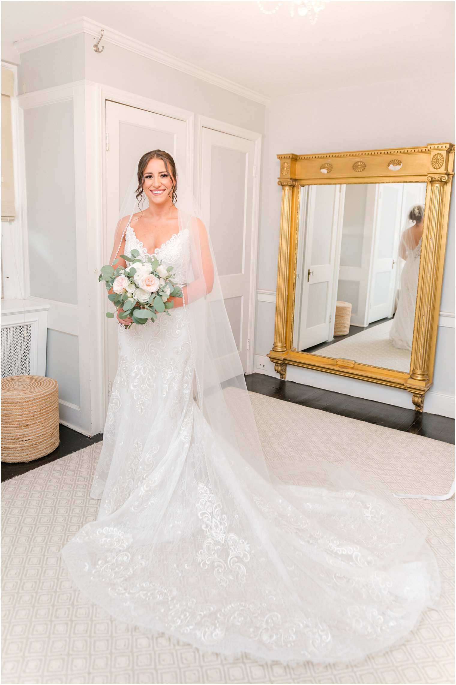bride stands by gold mirror in bridal suite at The Inn at Fernbrook Farms
