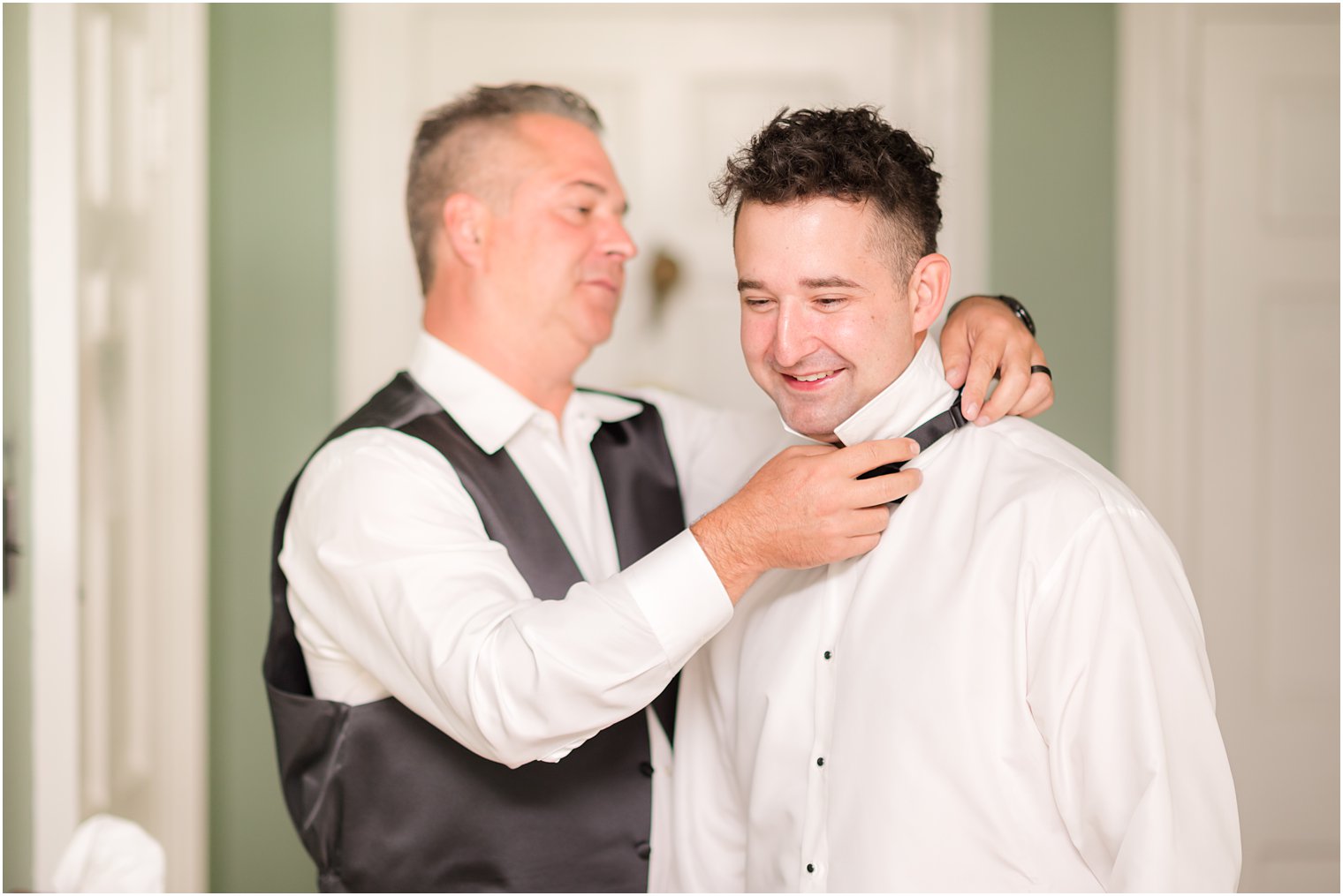 father helps groom with bowtie at The Inn at Fernbrook Farms