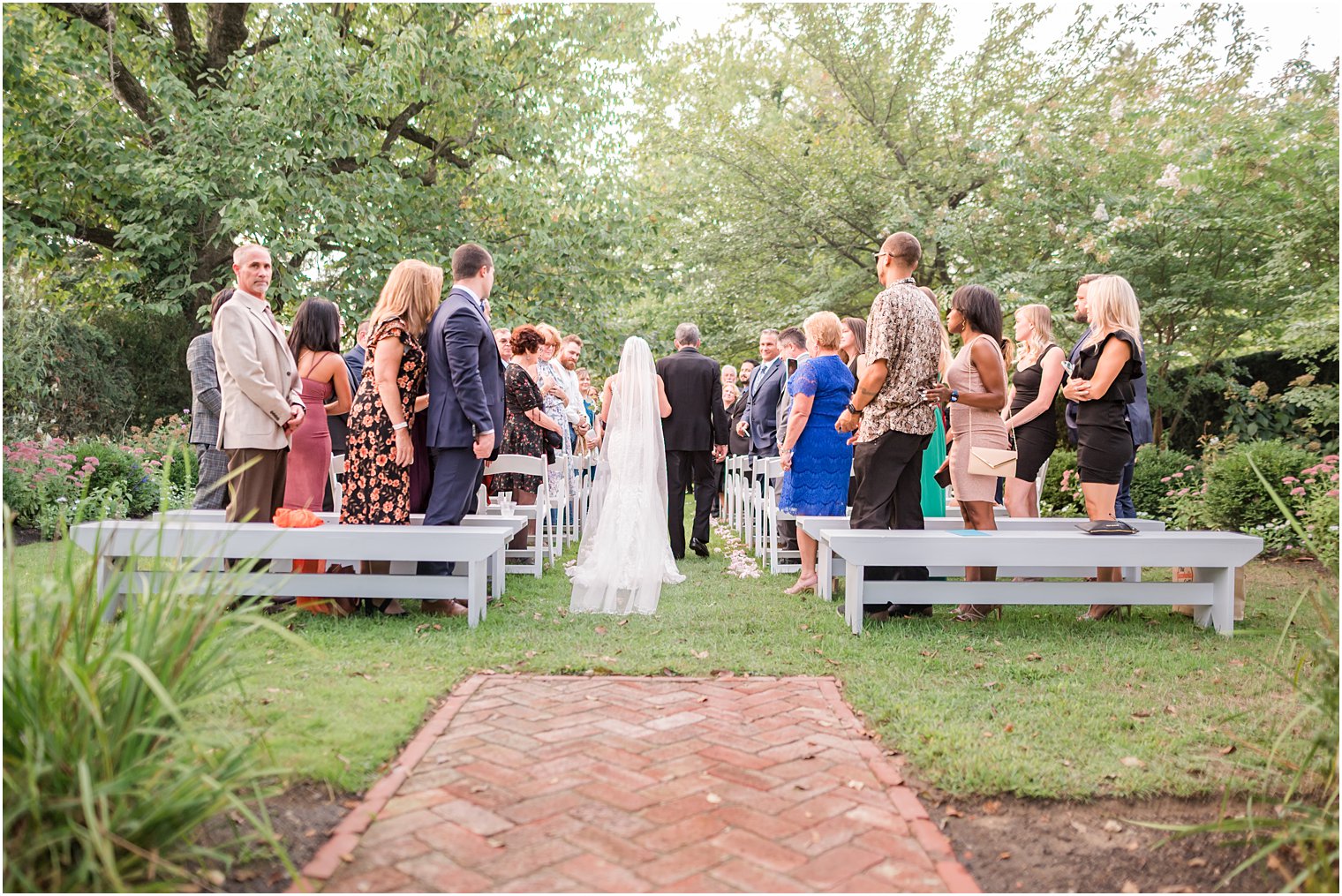 bride and father walk down aisle during wedding ceremony in garden at The Inn at Fernbrook Farms