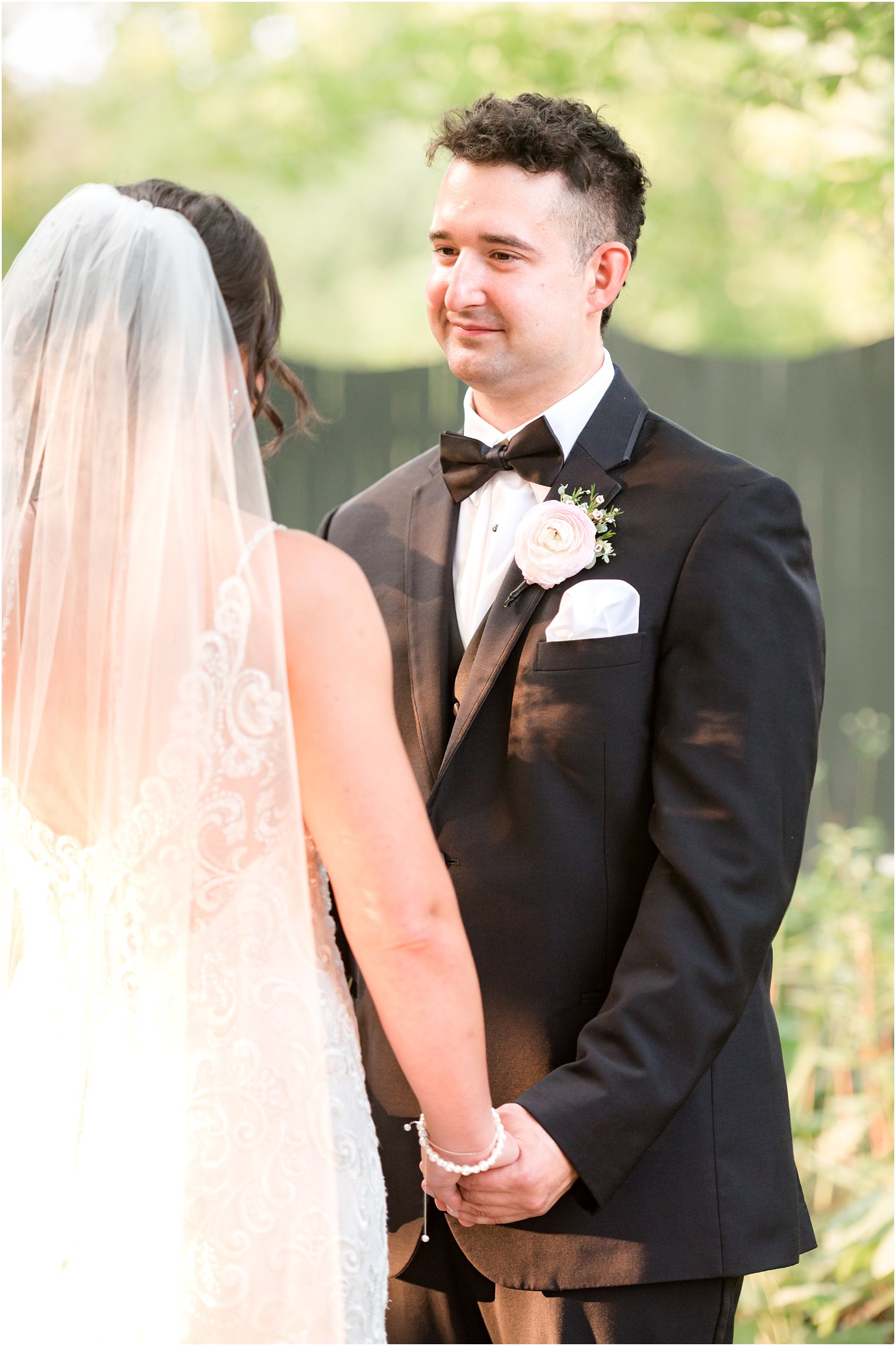 groom cries listening to vows during wedding ceremony in garden at The Inn at Fernbrook Farms