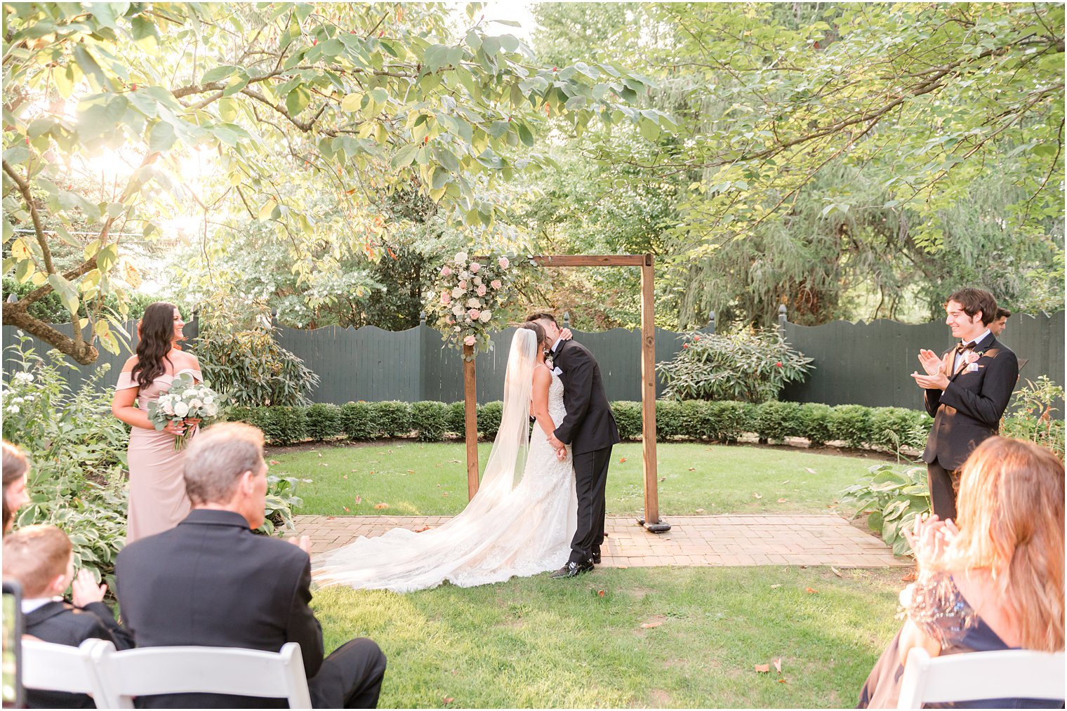 newlyweds kiss after wedding ceremony in garden at The Inn at Fernbrook Farms