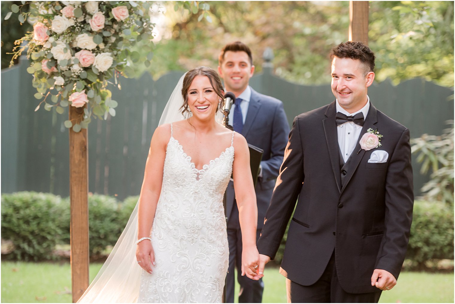 bride and groom smile at guests after wedding ceremony in garden at The Inn at Fernbrook Farms