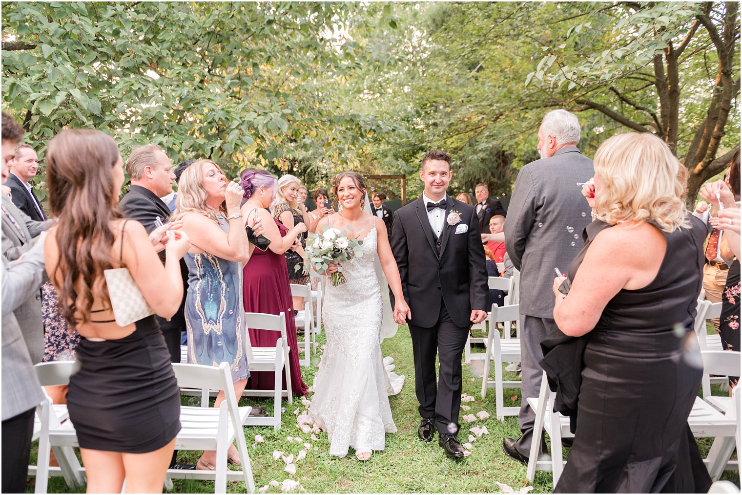 newlyweds walk up aisle after wedding ceremony in garden at The Inn at Fernbrook Farms