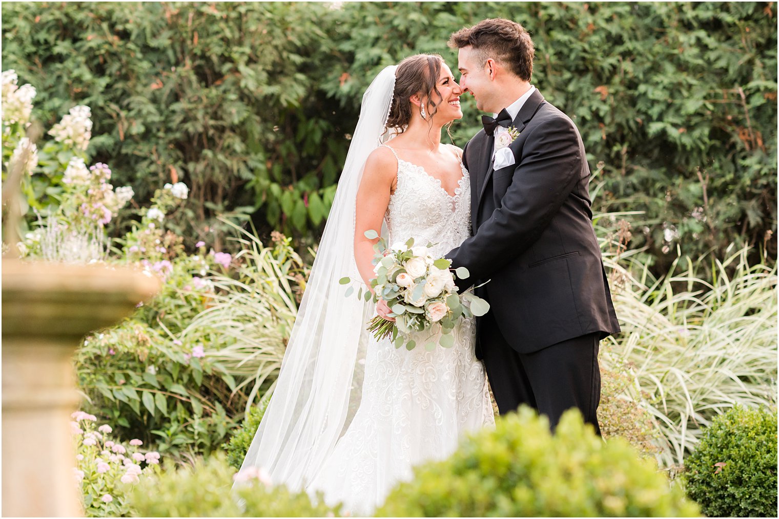 bride and groom lean in touching noses in gardens at The Inn at Fernbrook Farms