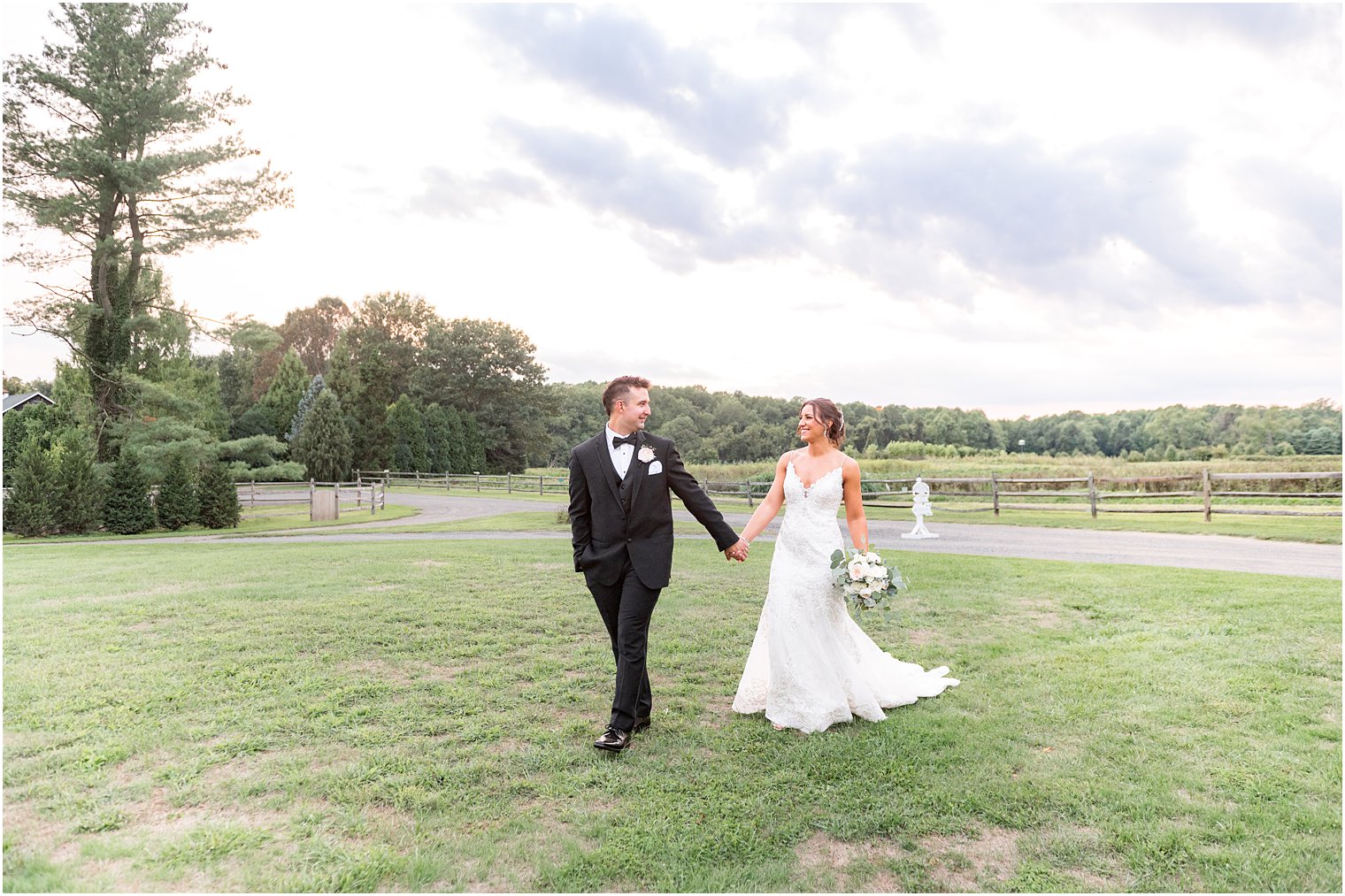 groom walks with bride across lawn at The Inn at Fernbrook Farms