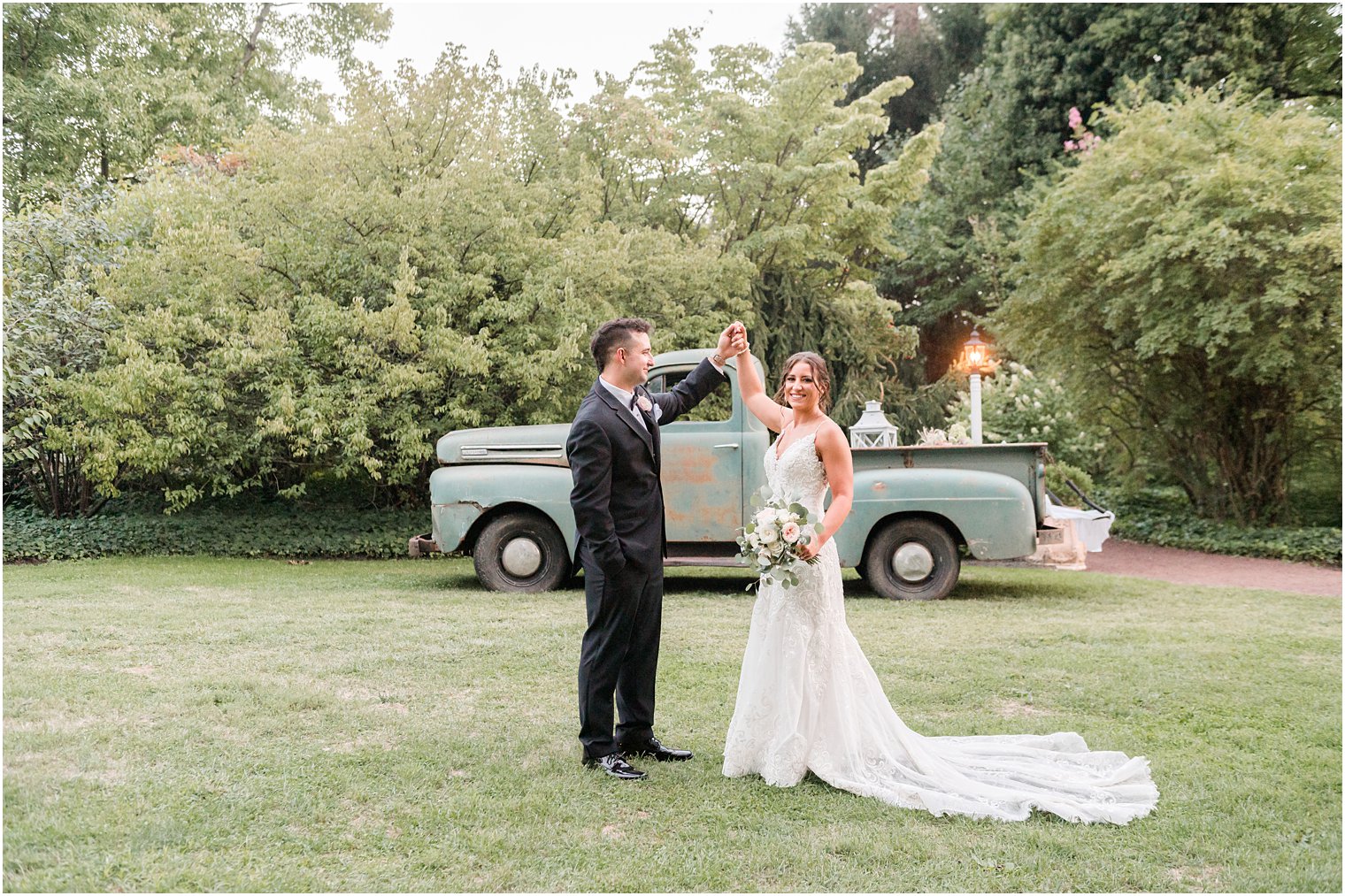 groom twirls bride by vintage green truck in New Jersey 
