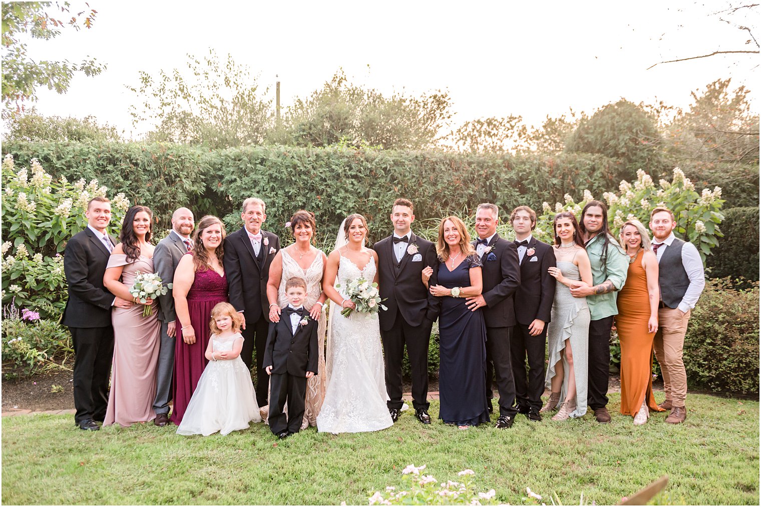 family stands with bride and groom in gardens at The Inn at Fernbrook Farms