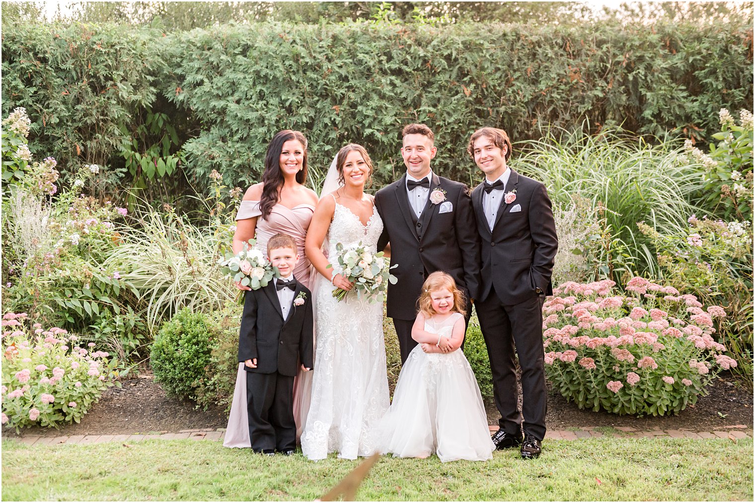 bride and groom pose with bridal party and flower girl