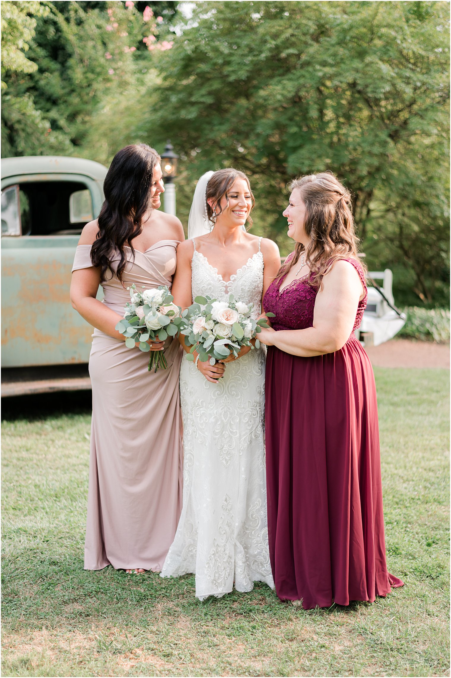 bride laughs with bridesmaids in pink and red gowns