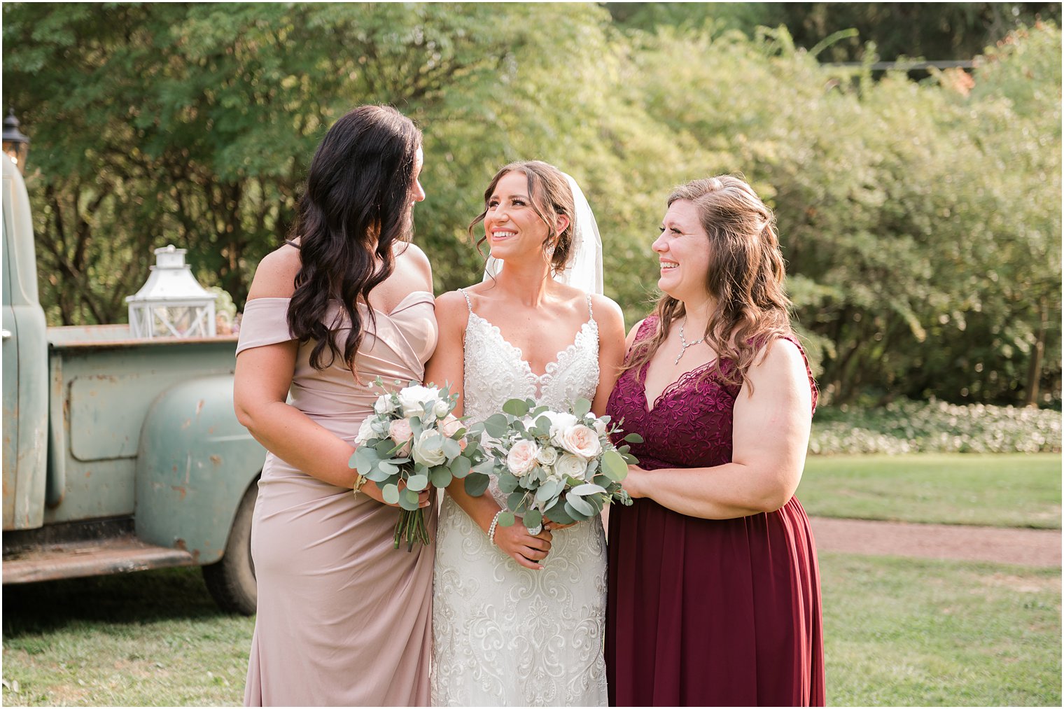 bride and bridesmaids smile standing by vintage green truck
