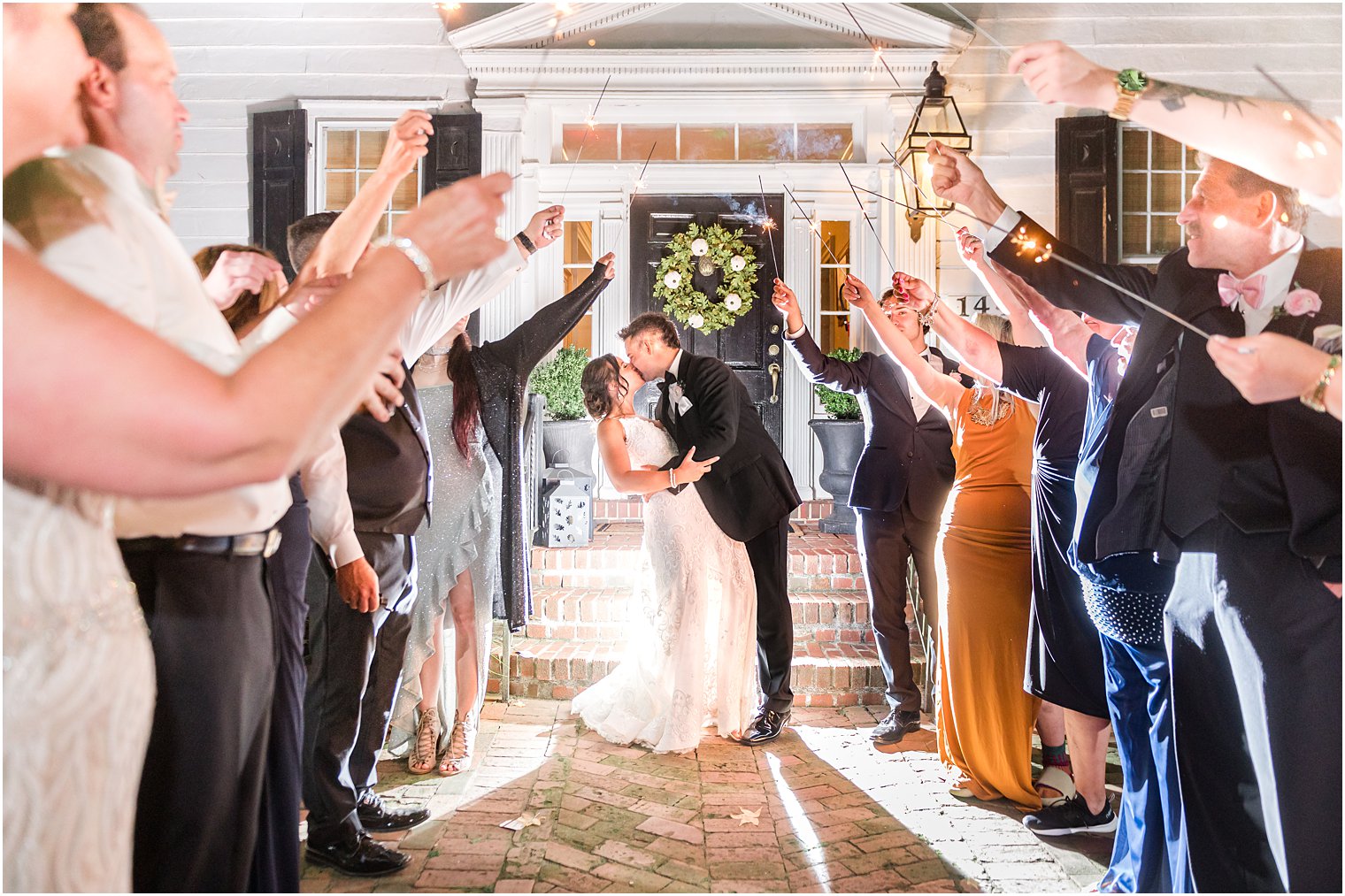 bride and groom kiss during sparkler exit in front of The Inn at Fernbrook Farms