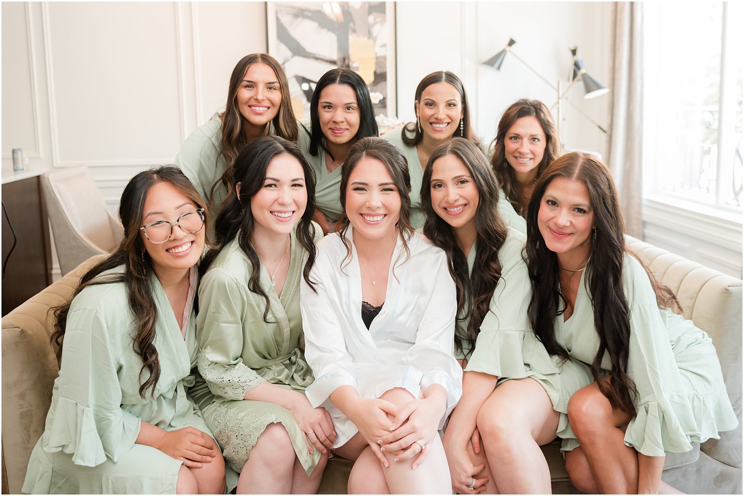 bride sits with bridesmaids in sage green robes 