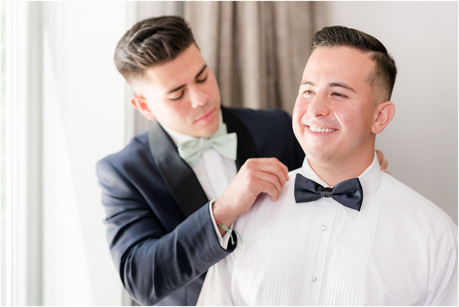 groomsman helps groom with bowtie 