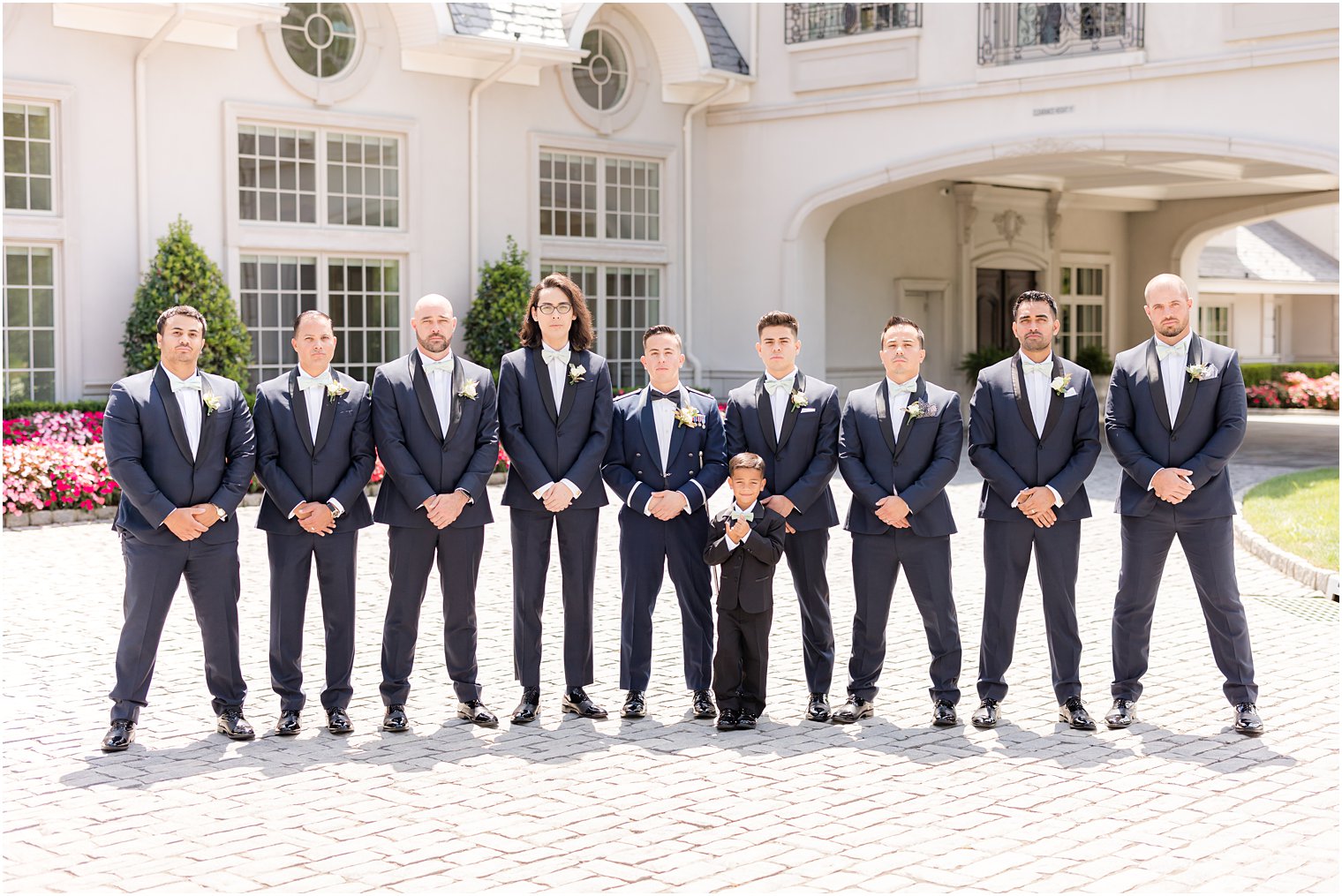 groom stands with groomsmen in blue suits 