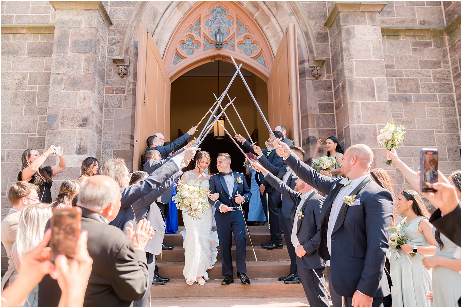 newlyweds leave wedding ceremony at St. Peter's Catholic Church under saber arch 