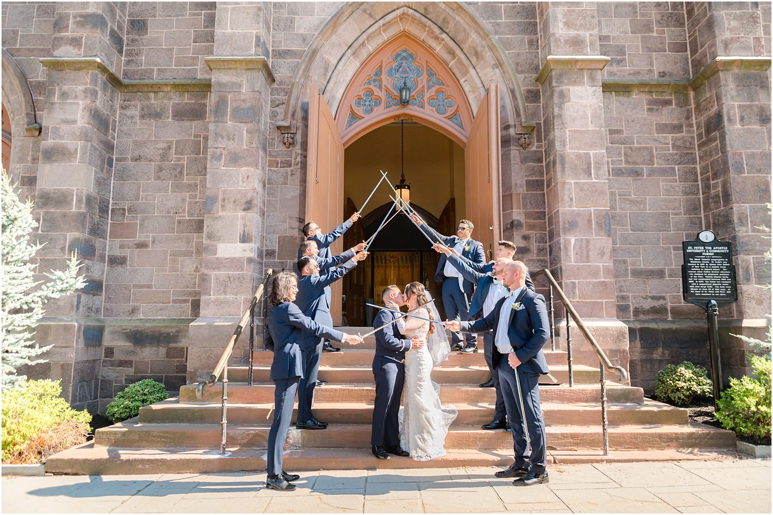 groomsmen create saber arch for bride and groom to kiss under at St. Peter's Catholic Church 