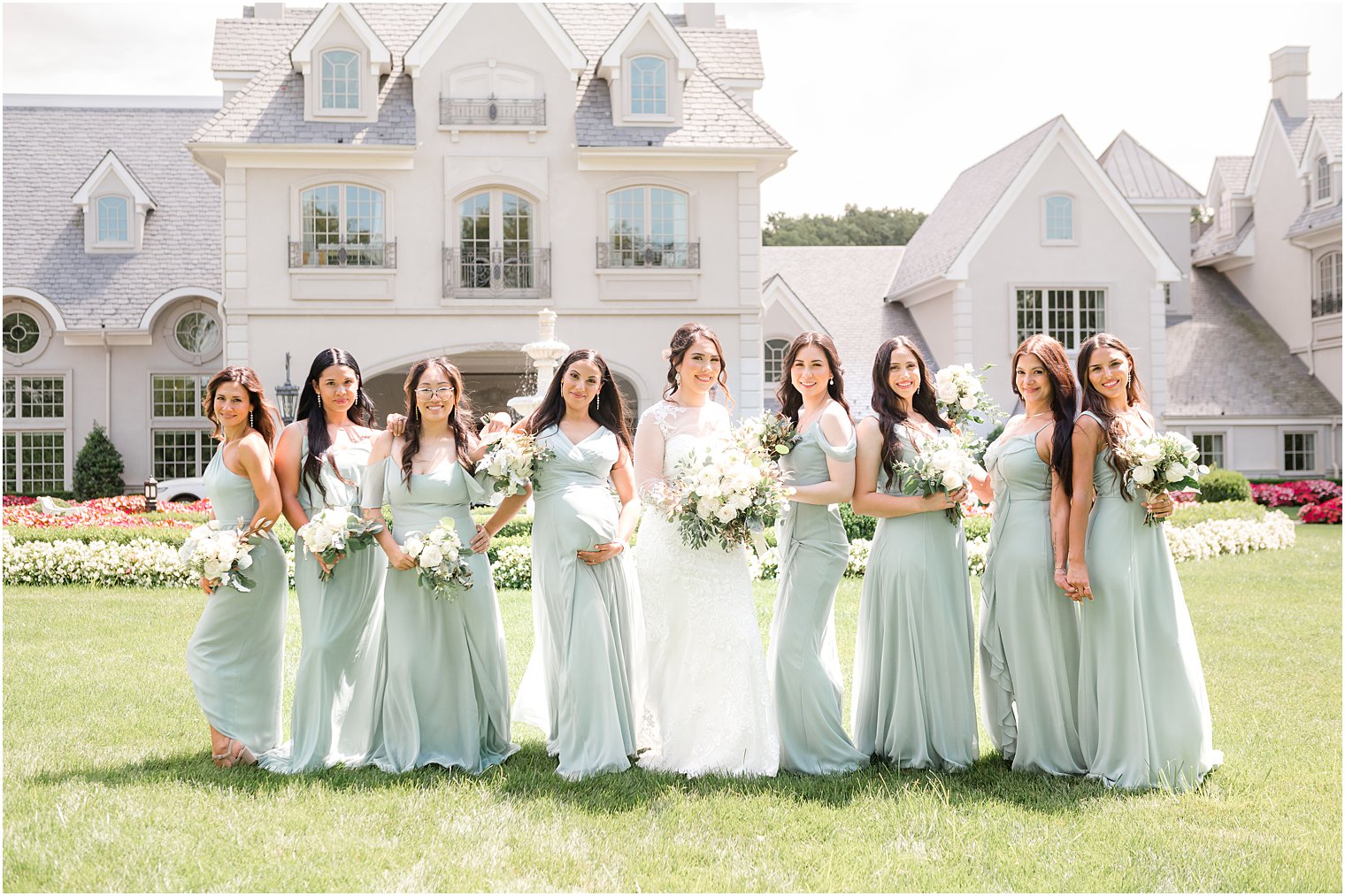 bride poses with bridesmaids in sage green gowns on lawn at Park Chateau Estate