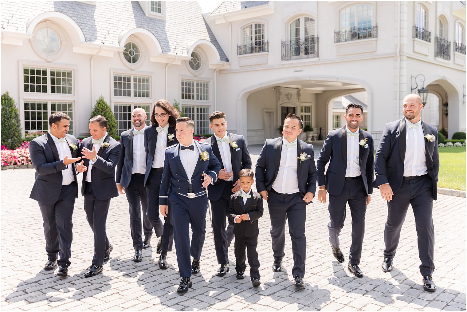 groom and groomsmen in military uniform and blue suits walk outside Park Chateau Estate
