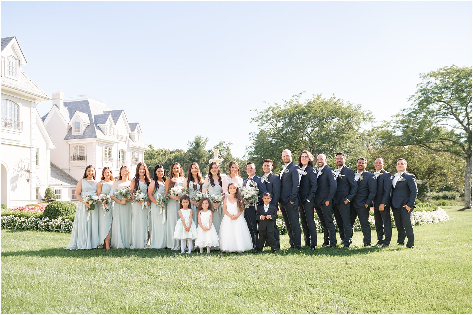bride and groom stand with wedding party on lawn at Park Chateau Estate