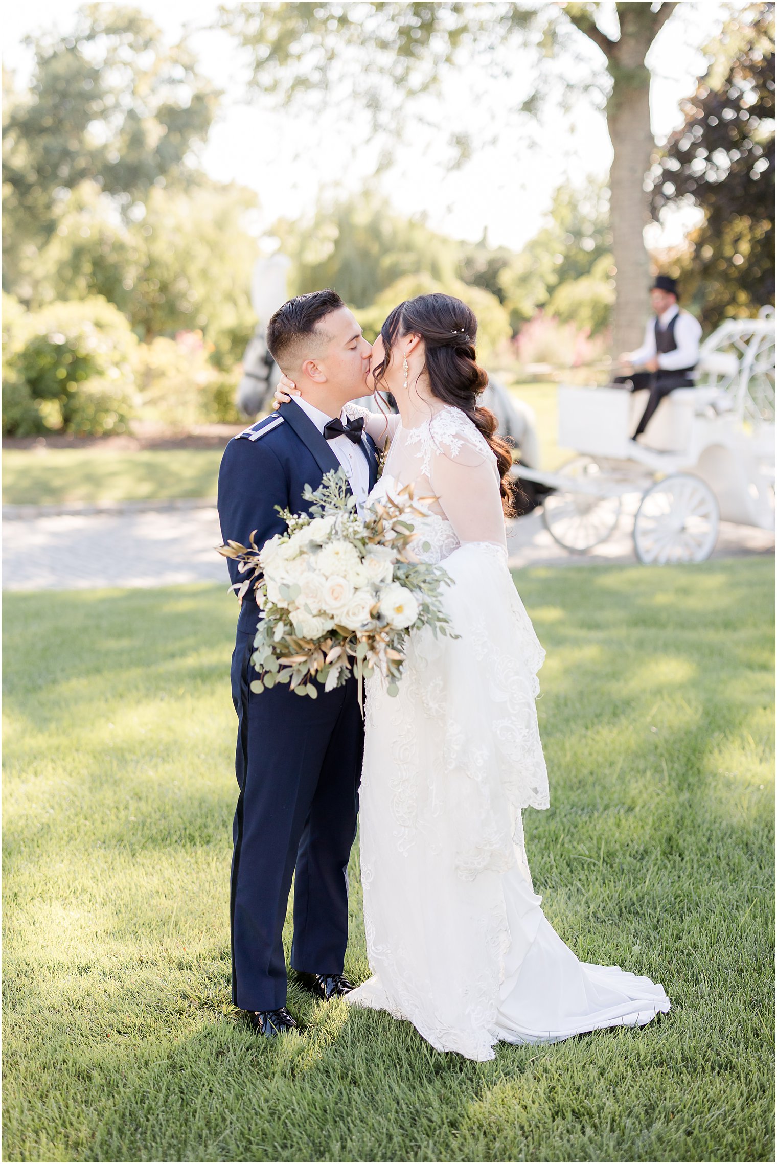 bride and groom kiss on lawn with carriage behind them at Park Chateau Estate
