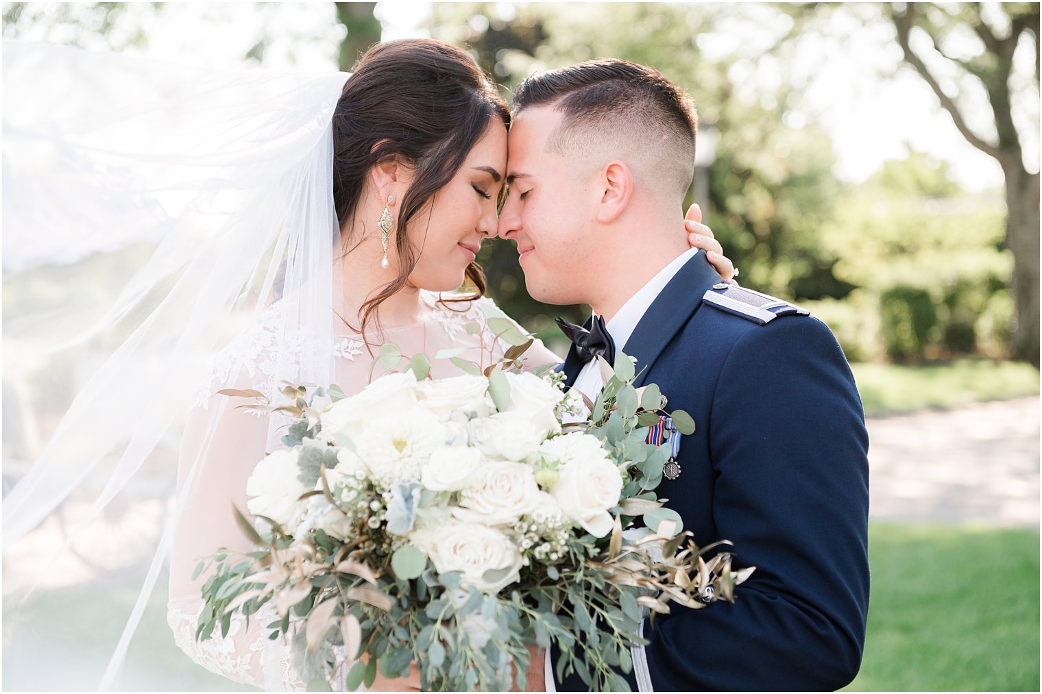newlyweds lean heads together touching noses during summer wedding portraits 